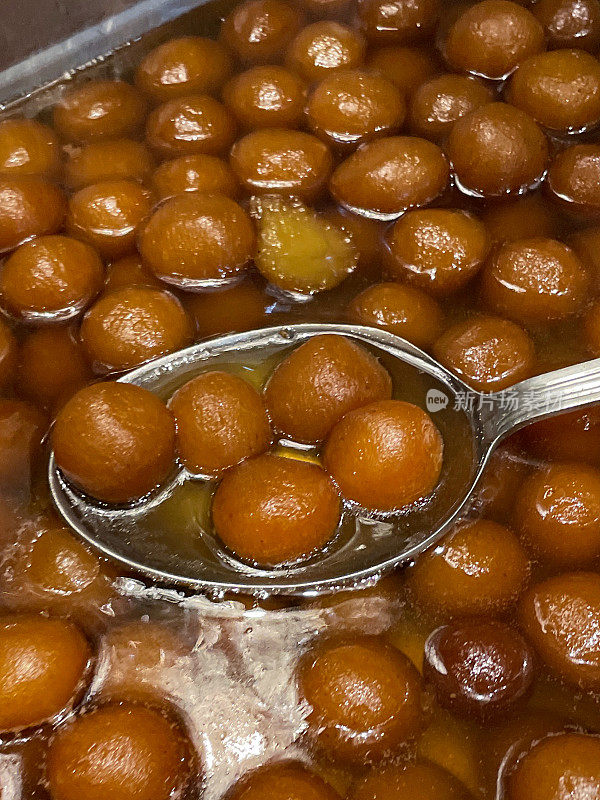 印度糖果店展示的Gulab jamun(玫瑰水浆果)Mithai(糖果)的餐饮托盘的全帧图像，浸泡在糖浆中(水，糖豆蔻，玫瑰水和藏红花)，高架视图，关注前景